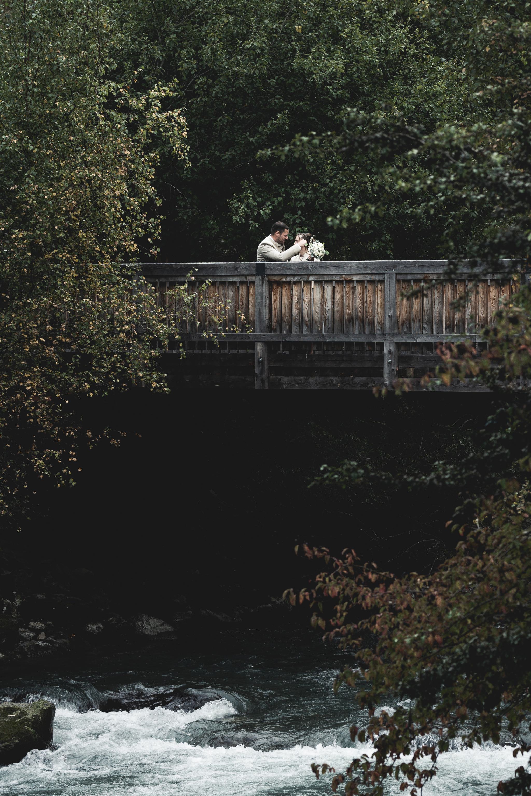 Brautpaar auf einer Holzbrücke, Kuss