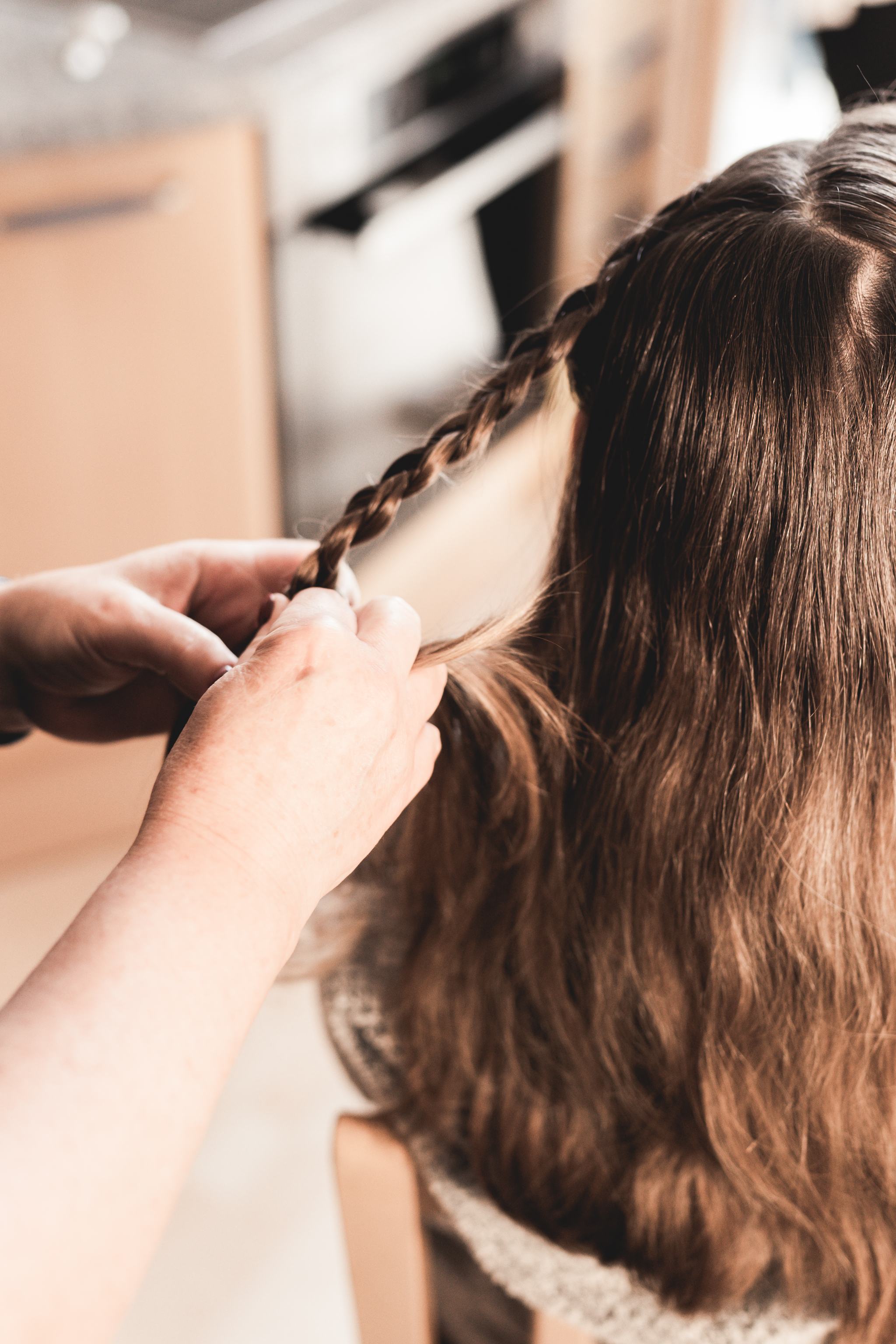 Hände flechten das Haar der Braut während der Vorbereitungen